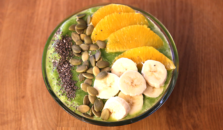Glassbolle med smoothie, med frukt og frø på toppen.